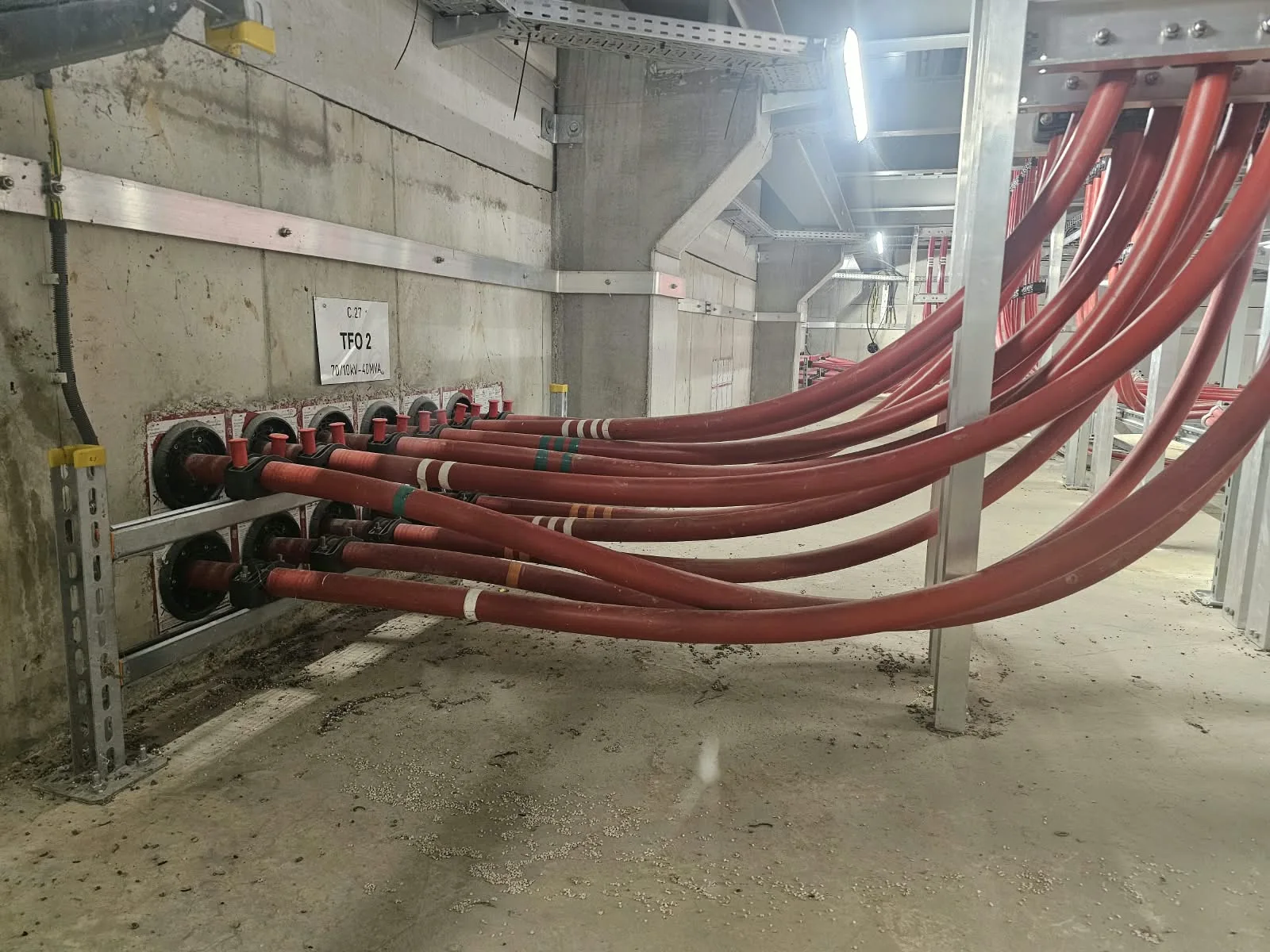 Rode vermogenskabels in een betonnen kabelkelder van een station